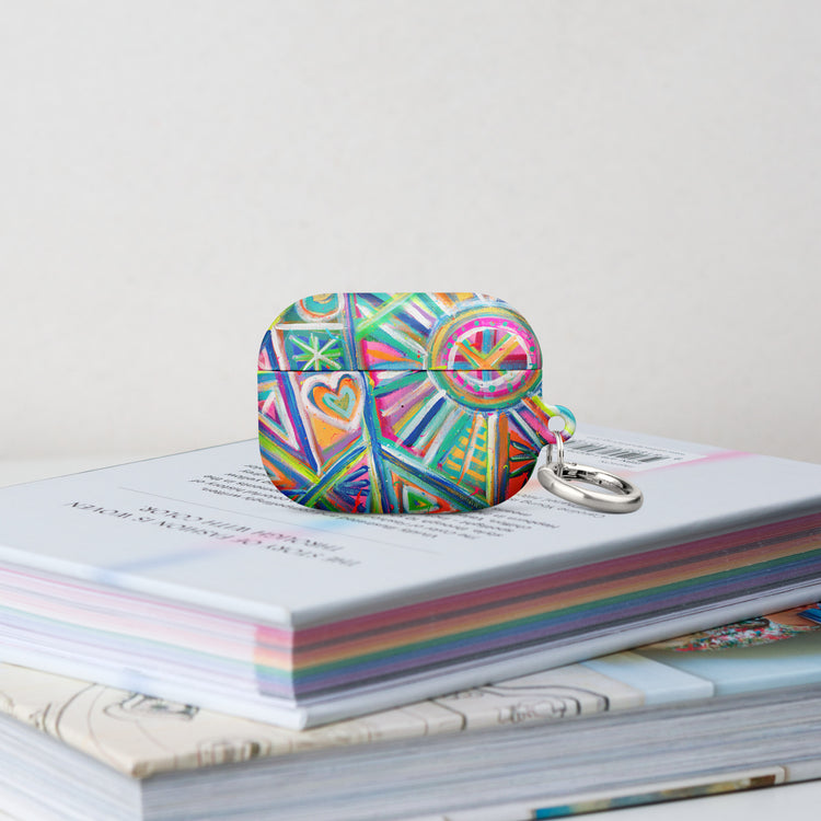 The Geometric Rainbow Airpods Pro Gen 1  Case stands on a stack of books.  It features  an abstract design of colourful green, pink, yellow, blue, and purple stripes, dots, and zigzags. 
