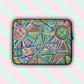 The Geometric Rainbow Laptop Sleeve by My Favourite Colour is Rainbow features vibrant abstract geometric patterns, including circles, triangles, and hearts, in bright pink, blue, green, and yellow. The print is on only one side of the laptop sleeve, the other side is black.