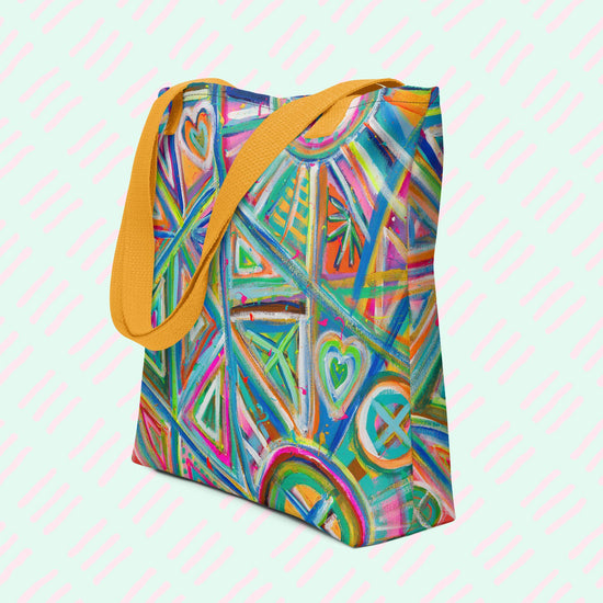 The Geometric Rainbow Tote Bag by My Favourite Colour is Rainbow features vibrant blue, green, orange, pink, and yellow geometric and heart patterns. This version has a yellow strap.