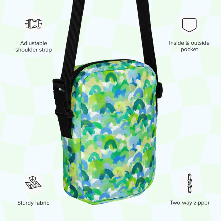 The Green Rainbow Mini Crossbody Bag by My Favourite Colour is Rainbow features a vibrant pattern, adjustable strap, inside/outside pockets, durable fabric, and a two-way zipper, with icons in the image background.