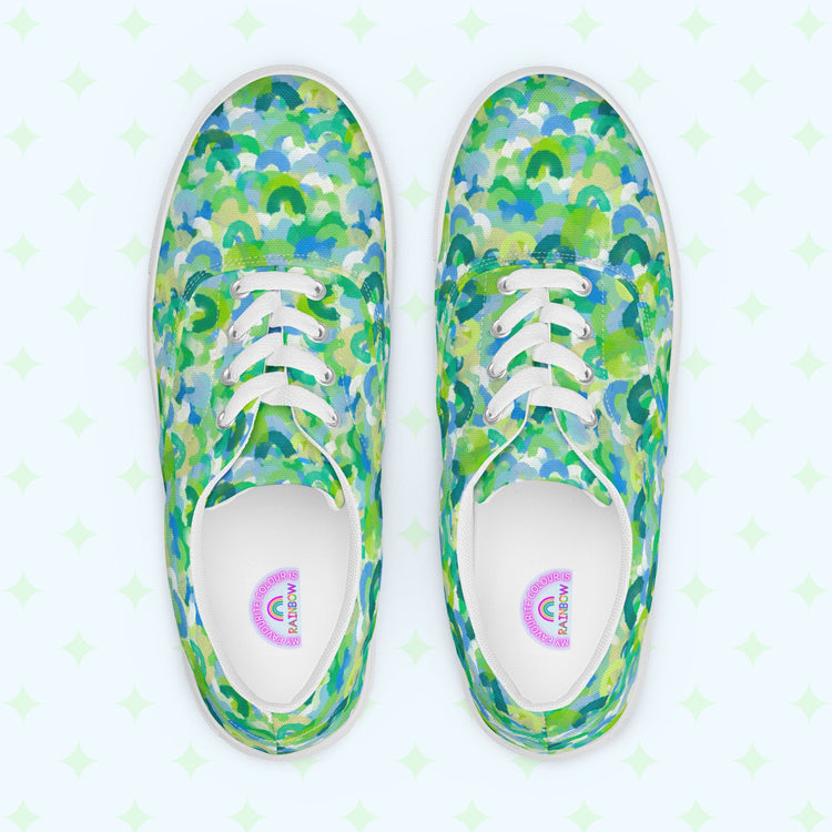 Top view of My Favourite Colour is Rainbows Green Rainbow Canvas Sneakers, featuring a vibrant green, blue, and white abstract pattern. The shoes have white laces and soles, with inner soles labeled GOLF, resting on a light background with subtle star-like designs.