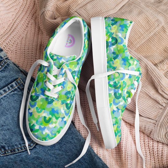 Green Rainbow Canvas Sneakers by My Favourite Colour is Rainbow feature a vibrant blue, green, and white pattern. They have white laces and soles, pairing perfectly with a beige sweater, while a hint of blue jeans adds contrast.