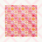 The Happy Smiles Sunny Days Bandana by My Favourite Colour is Rainbow features a vibrant pattern of smiley faces, lightning bolts, hearts, clouds, flowers, and waves on a pink and cream checkered background. 