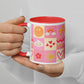 A person holds a My Favourite Colour is Rainbow Happy Smiles Sunny Days Mug, a white ceramic mug with a red interior and cheerful checkered squares featuring joyful images like rainbows, clouds, lightning bolts, hearts, flowers, and suns. Their nails are painted beige.