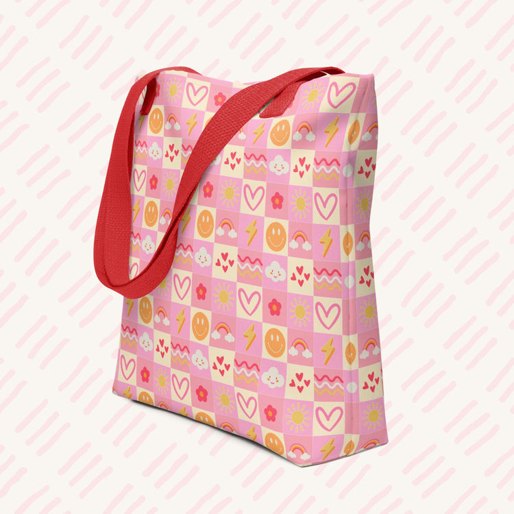 The Happy Smiles Sunny Days Tote Bag by My Favourite Colour is Rainbow features a pink design with a red strap and colourful patterns of hearts, smiley faces, lightning bolts, flowers, and clouds.