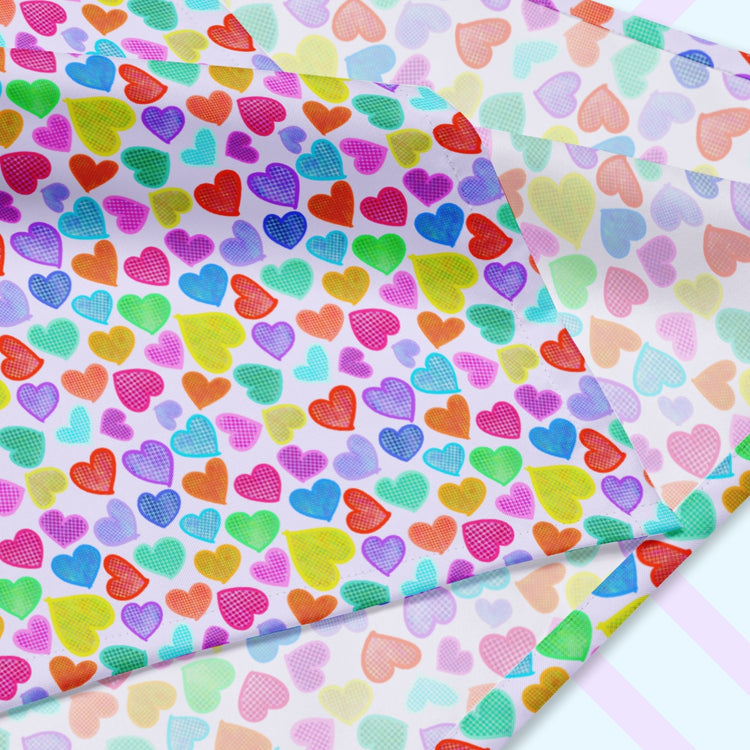 A closeup of the 'Heart Attack' Bandana by My Favourite Colour is Rainbow featuring a vibrant, cheerful pattern of densely packed, colourful hearts in pink, blue, purple, green, and orange on a light background. The design is printed on only one side of the bandana.
