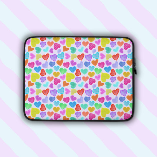 The Heart Attack Laptop Sleeve by My Favourite Colour is Rainbow features a vibrant heart pattern in red, blue, green, and purple over a light background.  The print is on only one side of the laptop sleeve, the other side is black.