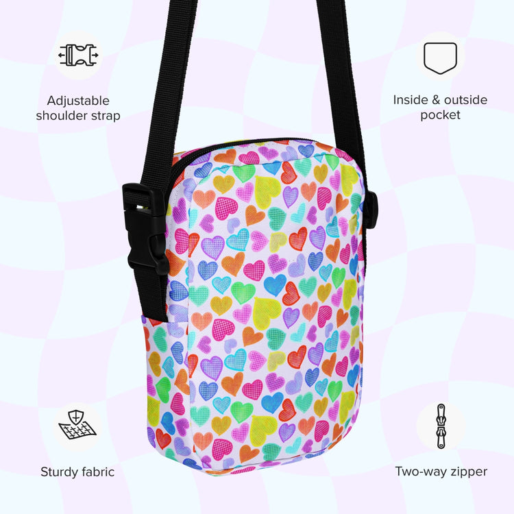 The Heart Attack Mini Crossbody Bag by My Favourite Colour is Rainbow showcases a vibrant Heart Attack print with multicolored hearts. It includes adjustable straps, a two-way zipper, plus inside and outside pockets, crafted from sturdy fabric.