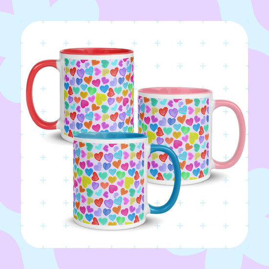 Three Heart Attack Mugs by My Favourite Colour is Rainbow feature vibrant multicoloured heart patterns on a light  backdground. Each mug has a differently coloured handle: red, blue, and pink.