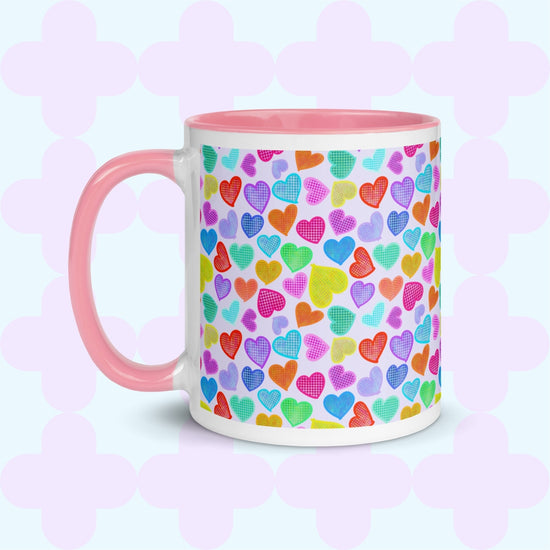 The Heart Attack Mug by My Favourite Colour is Rainbow features a pink interior and handle, with a vibrant pattern of overlapping hearts in bright blue, purple, yellow, and pink on a pastel background.