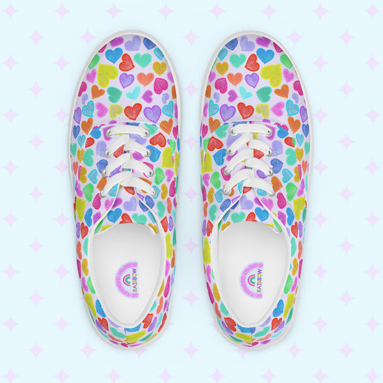 Introducing the My Favourite Colour is Rainbow's Heart Attack Canvas Sneakers, adorned with vibrant multicoloured hearts in red, blue, purple, and green. These sneakers feature white laces and soles.  The inside of the shoe is white with My Favourite Colour is Rainbow branding on the footbed.
