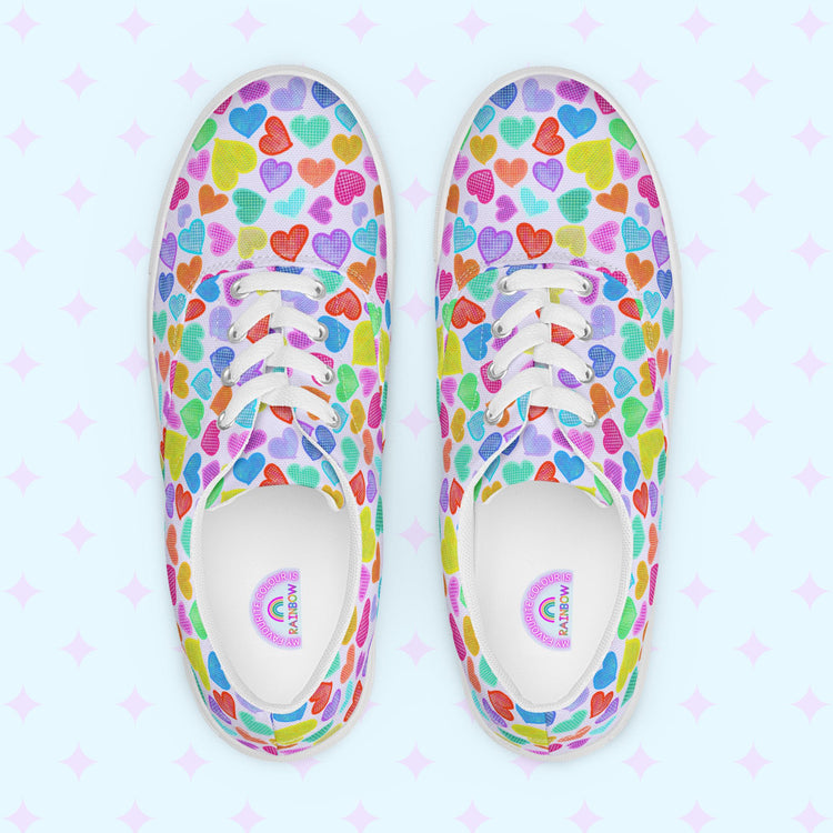 Introducing the My Favourite Colour is Rainbow's Heart Attack Canvas Sneakers, adorned with vibrant multicoloured hearts in red, blue, purple, and green. These sneakers feature white laces and soles.  The inside of the shoe is white with My Favourite Colour is Rainbow branding on the footbed.
