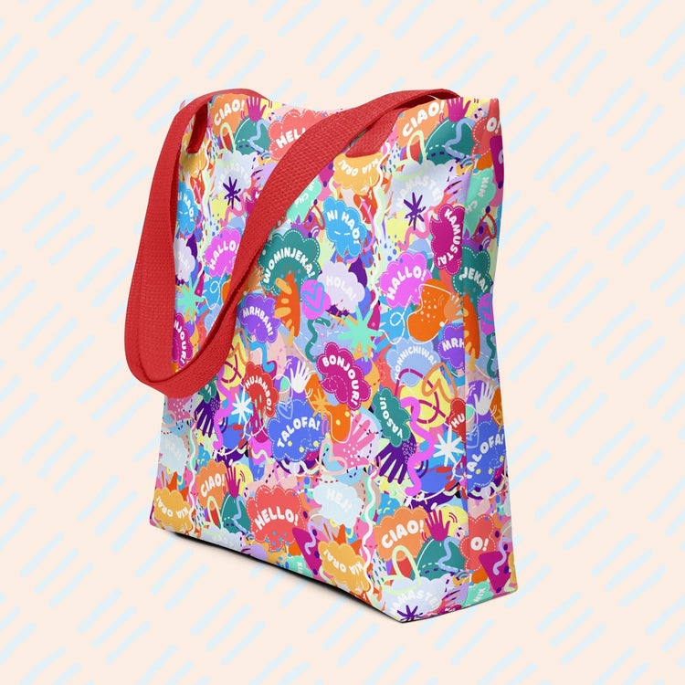 Hello! Wominjeka! Tote Bag by My Favourite Colour is Rainbow features bold abstract designs with "Hello" in various languages like hola and bonjour. It has a spacious design with a sturdy red strap.