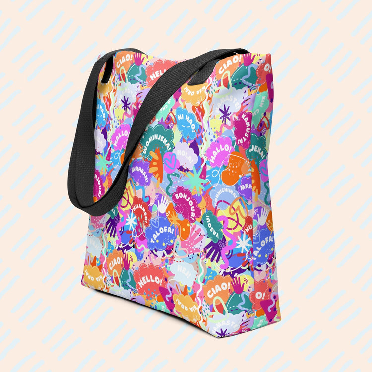 The Hello! Wominjeka! Tote Bag by My Favourite Colour is Rainbow features black straps and vibrant abstract designs with multilingual words such as Hello and Bonjour. 