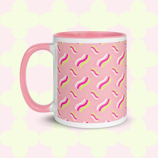 The Iced Vovo Mug by My Favourite Colour is Rainbow features a pink handle on a white and pink base, adorned with wavy lines in pink, yellow, and white against a pink background. 