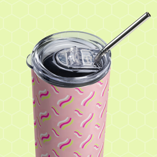 The Iced Vovo Stainless Steel Tumbler by My Favourite Colour is Rainbow has a pink body with wavy yellow and purple patterns, a clear rounded lid, and a sleek stainless steel straw. The backdrop is light green with a subtle hexagonal design.