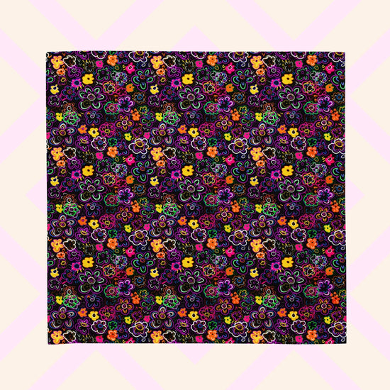 The 'In the Midnight Garden' Bandana by My Favourite Colour is Rainbow features a vibrant floral pattern with pink, orange, yellow, purple, and green flowers on a dark backdrop. 