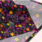 A close up of the 'In the Midnight Garden' Bandana by My Favourite Colour is Rainbow, featuring a vibrant floral pattern with pink, orange, yellow, purple, and green flowers on a dark backdrop.  The print is on only one side of the bandana.