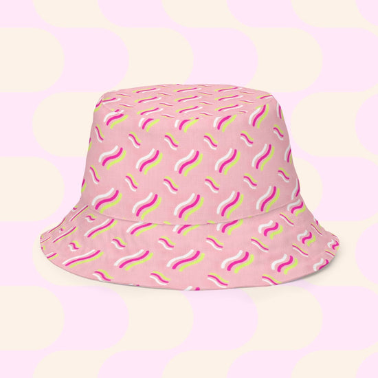 The In the Midnight Garden/Iced Vovo Reversible Bucket Hat by My Favourite Colour is Rainbow features a lively wavy pattern in white, yellow, and magenta against pink and cream circles. Available in multiple sizes, its the style BFF youve been seeking.