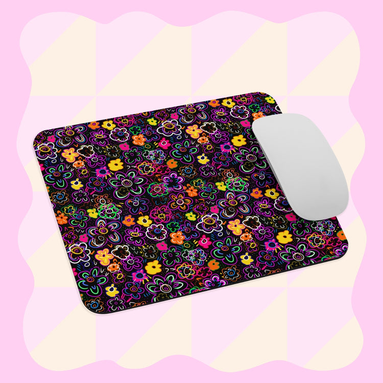 The In the Midnight Garden Mouse Pad by My Favourite Colour is Rainbow showcases a vibrant floral design against a light pink and yellow checkered background, with a white computer mouse placed on the pads right side.