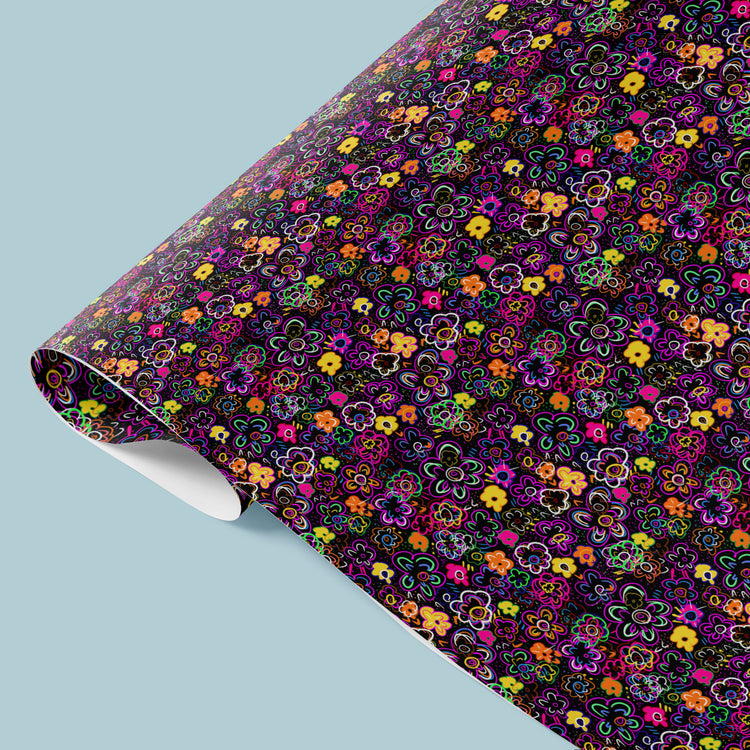 The In the Midnight Garden Wrapping Paper Sheets by My Favourite Colour is Rainbow feature neon pink, purple, orange, and green flowers on a black background, adding an eye-catching touch to your gifting.