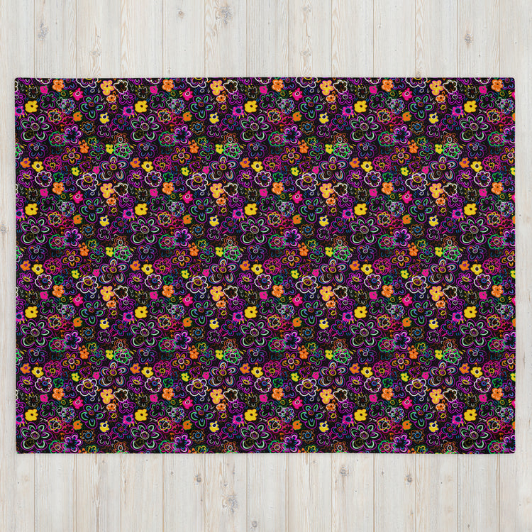 The In the Midnight Garden Throw Blanket by My Favourite Colour is Rainbow boasts colorful, intricate floral patterns in purple, pink, yellow, green, and orange against a dark background. It adds a vibrant touch to any light wooden floor with its cozy fabric warmth.