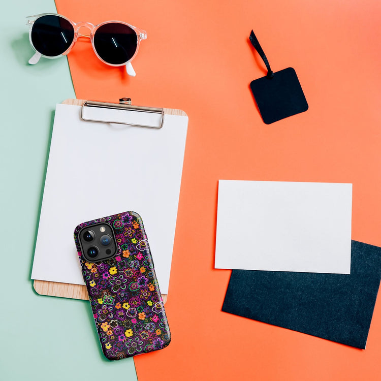 Flat lay of a wooden clipboard with white paper, black sunglasses, and the In the Midnight Garden MagSafe iPhone Case by My Favourite Colour is Rainbow. A blank white card and a black tag sit on the split orange and light green background.