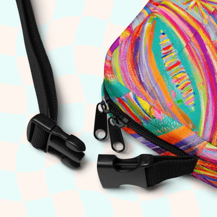 A close-up of the Karma Kaleidoscope Mini Crossbody Bag from My Favourite Colour is Rainbow, showing the black buckle.  It is made of canvas-type material, has internal and external pockets and an adjustable black strap with a buckle on one side that can be extended to crossbody length.