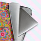 A close up of the 'Love in Neon' Laptop Sleeve by My Favourite Colour is Rainbow, opened, showing a silver laptop and grey interior.  It features a colourful abstract design with vivid paint strokes, heart shapes and flowers in bright yellow, pink, and orange.  The print is on only one side of the laptop sleeve, the other side is black.