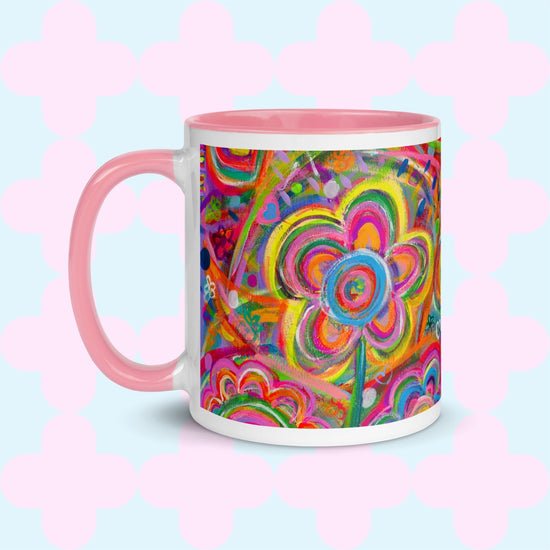 The Love in Neon Mug by My Favourite Colour is Rainbow features my Love in Neon painting with bold floral and heart patterns in vibrant pink, yellow, blue, and green. It has a light pink handle and interior.