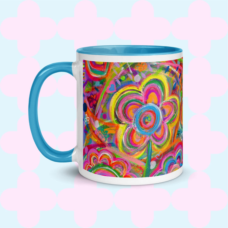 The Love in Neon Mug by My Favourite Colour is Rainbow features my Love in Neon painting with bold floral and heart patterns in vibrant pink, yellow, blue, and green. It has a light blue handle and interior.