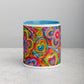 Front view of the Love in Neon Mug by My Favourite Colour is Rainbow, featuring a vibrant, multicoloured flower and heart design. The interior is light blue, and the mug rests against a neutral grey background on a light grey surface.