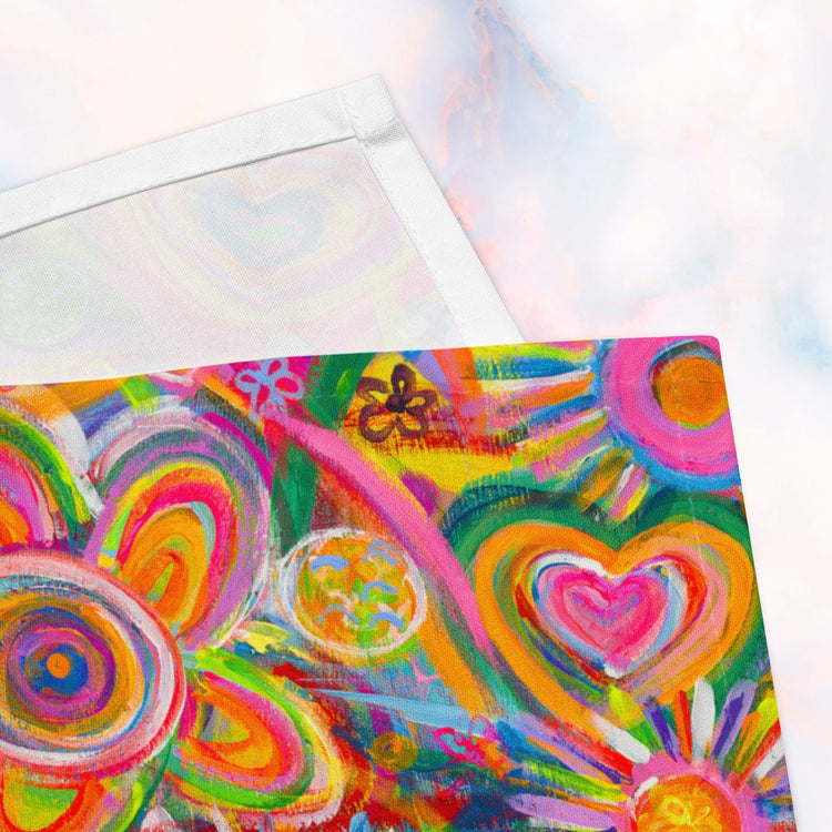 A close up of the Love in Neon cloth napkins by My Favourite Colour is Rainbow, featuring vibrant abstract designs in pink, orange, yellow, and green with heart and flower patterns. Ideal for brightening up dining spaces and sparking lively conversations.