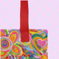 A close-up of the Love in Neon Tote Bag by My Favourite Colour is Rainbow showing the sturdy read handle and part of the design featuring my Love in Neon painting, with vibrant hearts and abstract flowers in pinks, greens, yellows, and blues. 