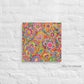 Love in Neon Canvas Artwork by My Favourite Colour is Rainbow features a vibrant 16x16 canvas with overlapping hearts and flowers in pink, yellow, blue, and green, standing out against a white brick wall.