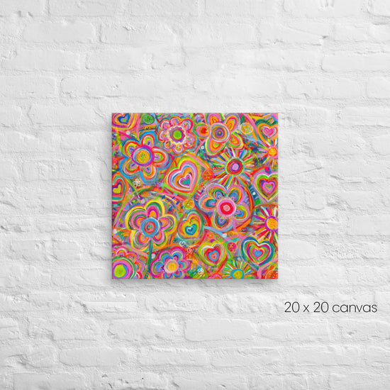 The Love in Neon Canvas Artwork by My Favourite Colour is Rainbow features a 20x20 canvas with abstract flowers, hearts, and swirls against a white brick wall. The piece bursts with vibrant pinks, yellows, greens, and blues.