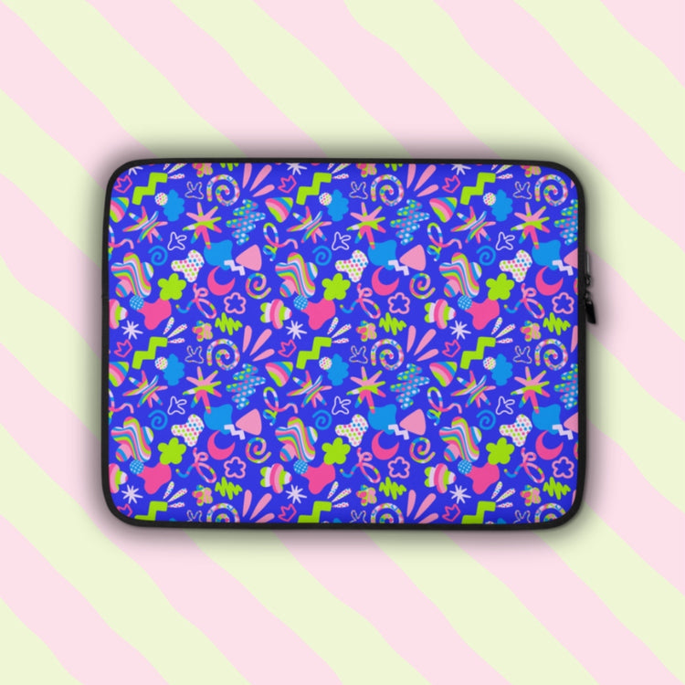 The Neon Carnival Laptop Sleeve by My Favourite Colour is Rainbow features vibrant abstract shapes, lines and doodles in pink, green, blue and white on a bright blue background. The laptop sleeve is shown on a pastel background.  The print is on only one side of the laptop sleeve, the other side is black.