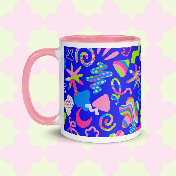 The Neon Carnival Mug by My Favourite Colour is Rainbow features vibrant abstract shapes and doodles in green, blue and white on a blue backdrop.  This version has a light pink handle and interior.