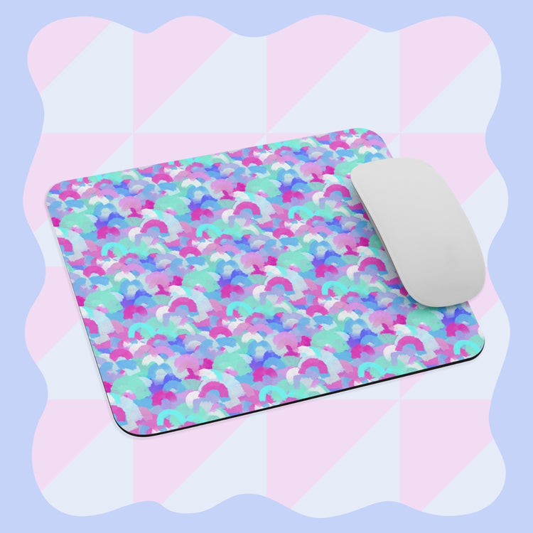 The Pastel Rainbow Mouse Pad by My Favourite Colour is Rainbow features a white computer mouse set against a vibrant pattern of overlapping arcs in purple, blue, and pink with a light pastel checkered design in the background.