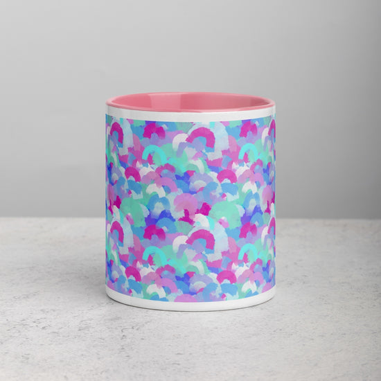 A front view of the Pastel Rainbow Mug by My Favourite Colour is Rainbow, featuring a light pink interior and soft watercolour rainbows in pink, blue, aqua and white. Its set on a light grey surface against a plain grey background.