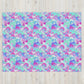 A cozy space is adorned with a vibrant design of overlapping pastel semicircles in pink, blue, purple, and green, reminiscent of the Pastel Rainbow Throw Blanket by My Favourite Colour is Rainbow against a light wooden backdrop.
