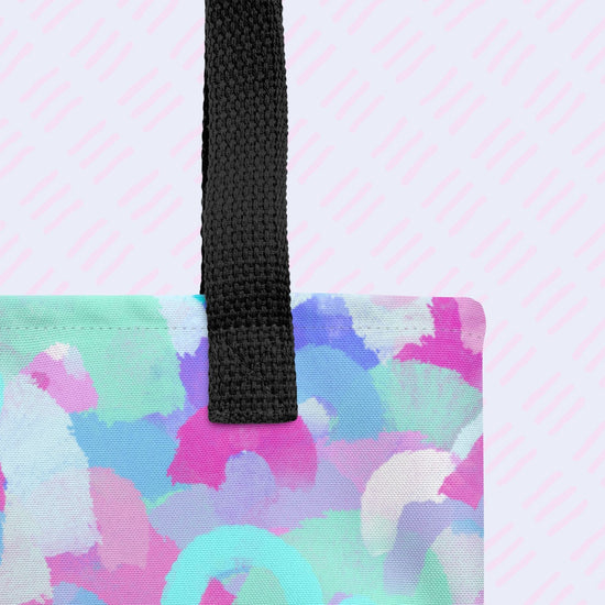 A close-up of the Pastel Rainbow Tote Bag by My Favourite Colour is Rainbow showing the sturdy black handle. The tote features watercolour pastel rainbows in shades of blue, purple, pink, and teal.  