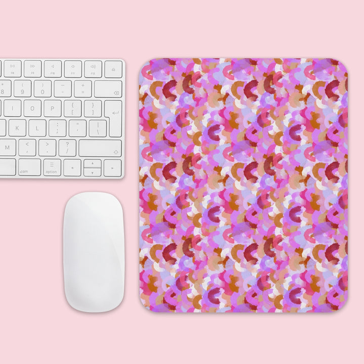 A white keyboard and mouse sit next to the Pink Rainbow Mouse Pad by My Favourite Colour is Rainbow, featuring a pink, purple, and brown abstract design on a light pink surface.