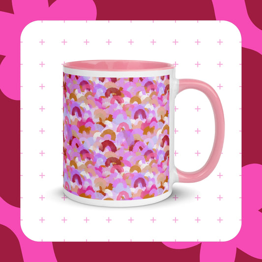 The Pink Rainbow Mug by My Favourite Colour is Rainbow features an abstract design of rainbow brushstrokes in shades of pink, burgundy, and gold and a pink handle and rimThe mug is shown on a background of pink crosses and a maroon border featuring pink shapes.