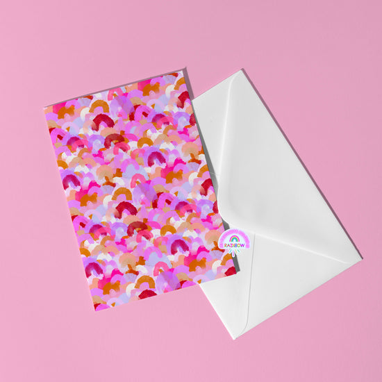 The Pink Rainbow Greeting Card by My Store showcases abstract arcs in red and purple hues on a soft pink background. Tucked in a white envelope with a rainbow sticker, its an ideal addition to your gift collection.