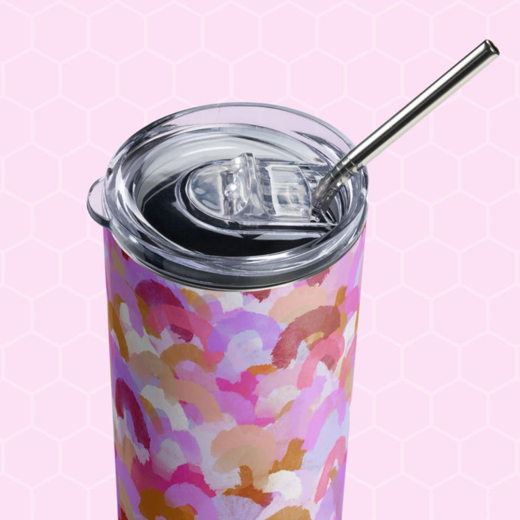 The Pink Rainbow Stainless Steel Tumbler by My Favourite Colour is Rainbow, features a pattern of pink, purple, and orange brush strokes. Its paired with a metal straw and clear lid against a light pink hexagonal patterned background.