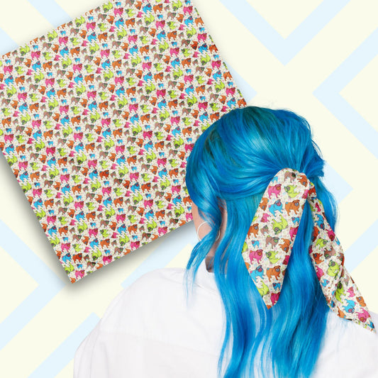 Two views of the 'Pugalicious' Bandana by My Favourite Colour is Rainbow.  At top left, a flat lay of the bandana.  At bottom right, a person with vibrant blue hair is seen from behind, wearing the bandana in her hair.  The bandana features a design of vibrant orange, blue, green, and pink pugs on a pale yellow background.