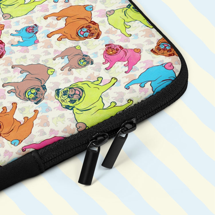 A close-up of the Pugalicious Laptop Sleeve by My Favourite Colour is Rainbow, featuring cartoon pugs with vibrant green, pink, blue, and orange hues.  It has two black zips and a padded zipper binding.  The print is on only one side of the laptop sleeve, the other side is black.  It is shown on a pastel background.