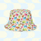 The Pugalicious Reversible Bucket Hat by My Favourite Colour is Rainbow showcases cartoon pugs in blue, green, orange, and pink on a light background with a blue and cream abstract pattern. This playful streetwear accessory is crafted from breathable fabric.