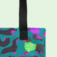 A close-up of the Silly Sausages Tote Bag by My Favourite Colour is Rainbow, featuring dachshunds in green and purple sweaters on a teal background. The tote has a black handle.